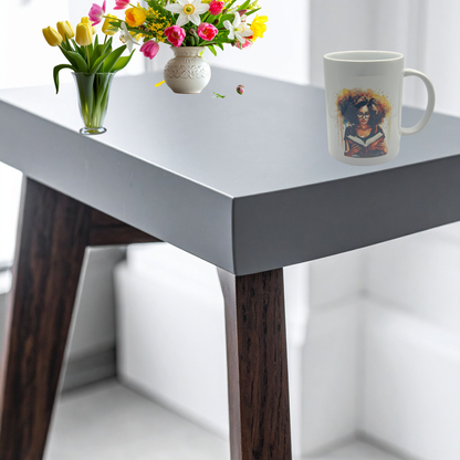 White table with wooden legs, a mug with a colorful design, and two flower arrangements.