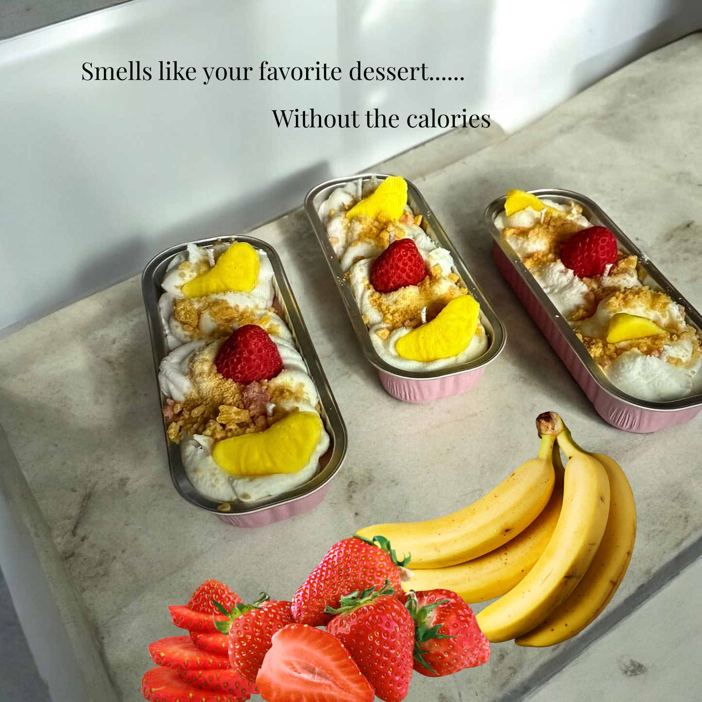 Three small containers of dessert with fruit on a stone surface, surrounded by bananas and strawberries.